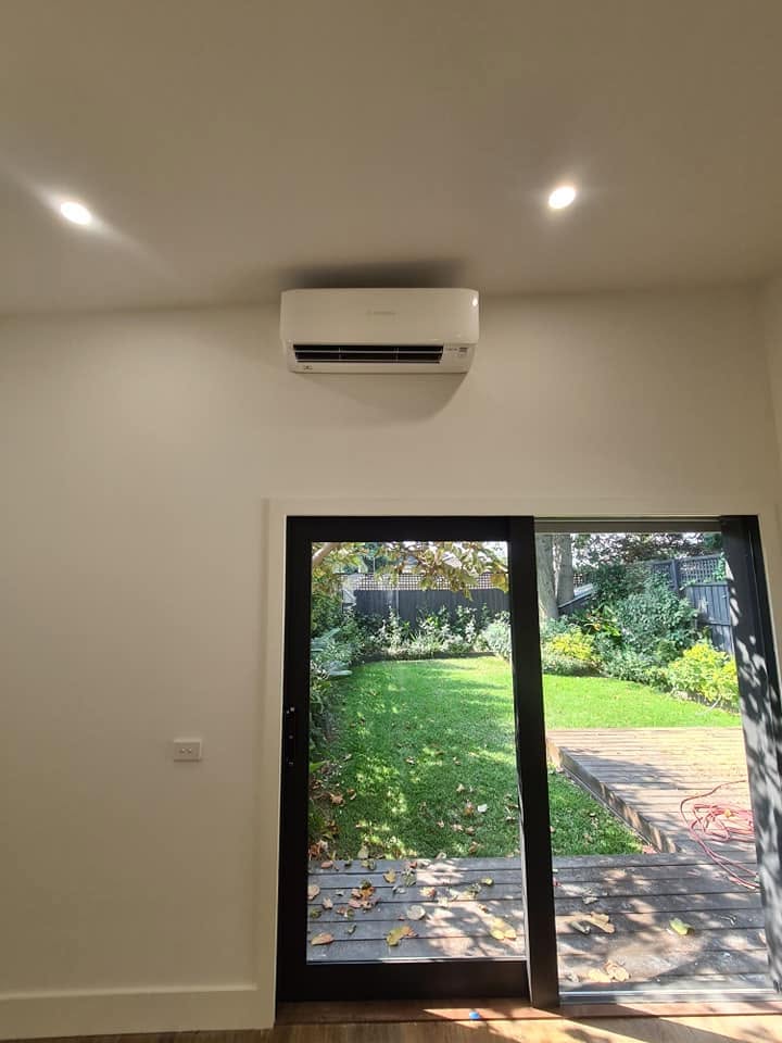 A finished indoor split system head above sliding doors to a garden