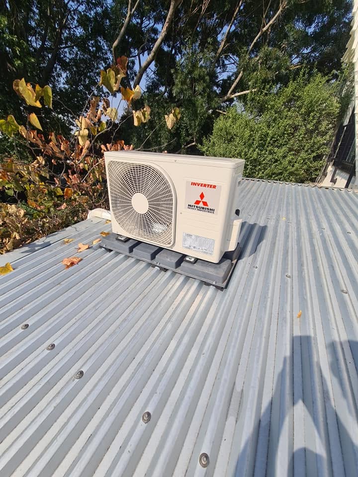 A Mitsubishi outdoor unit mounted on a corrugated iron roof