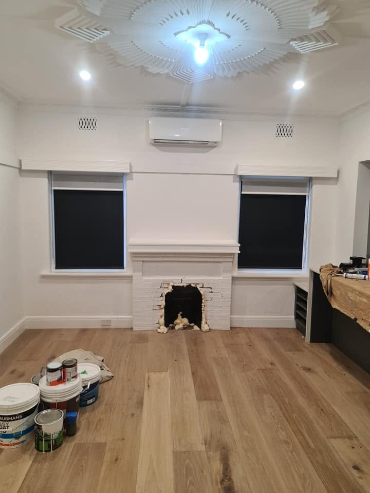 A split system on the wall of a renovated period room, under a decorative ceiling rose